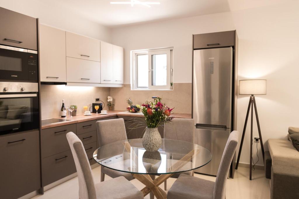 una cocina con una mesa de cristal con un jarrón de flores en Al Santo Apartments en Zakynthos