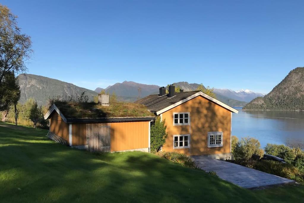 a house on a hill next to a body of water at Moonvalley Lodge - stort & koselig hus - Måndalen in Sæbø