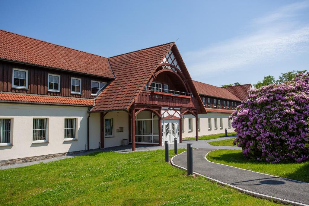 a building with a red roof and a green yard at Sportschule Werdau in Werdau