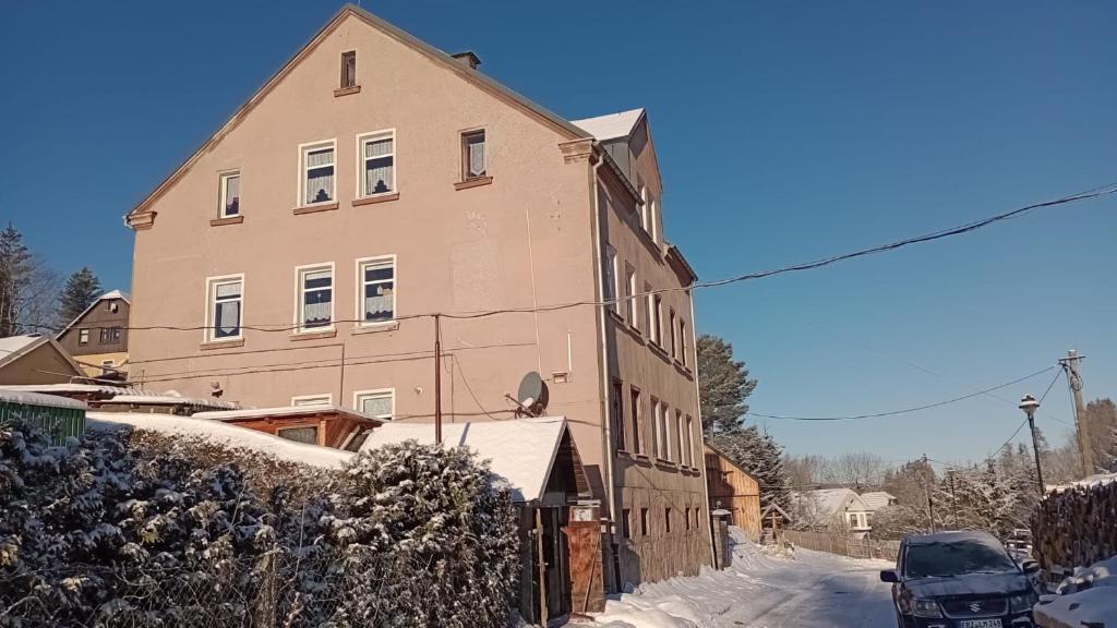 un grande edificio con neve di fronte di Ferienwohnung Rüfflerstub a Eibenstock