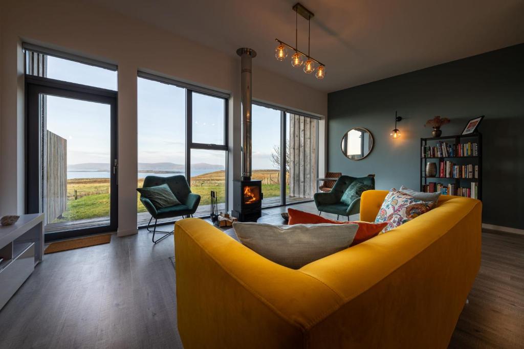 a living room with a yellow couch and windows at Silverwood Waternish in Portree