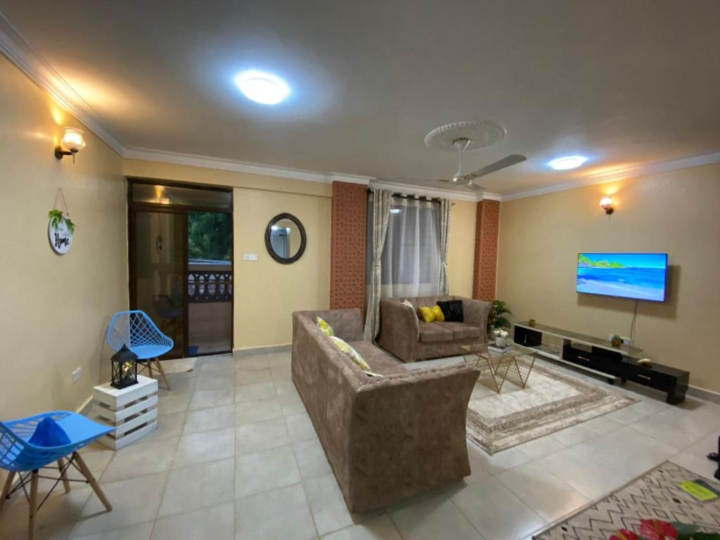 a living room with a couch and a tv at Lovely and homely 2 bedroom Serviced Apartment in Kilifi