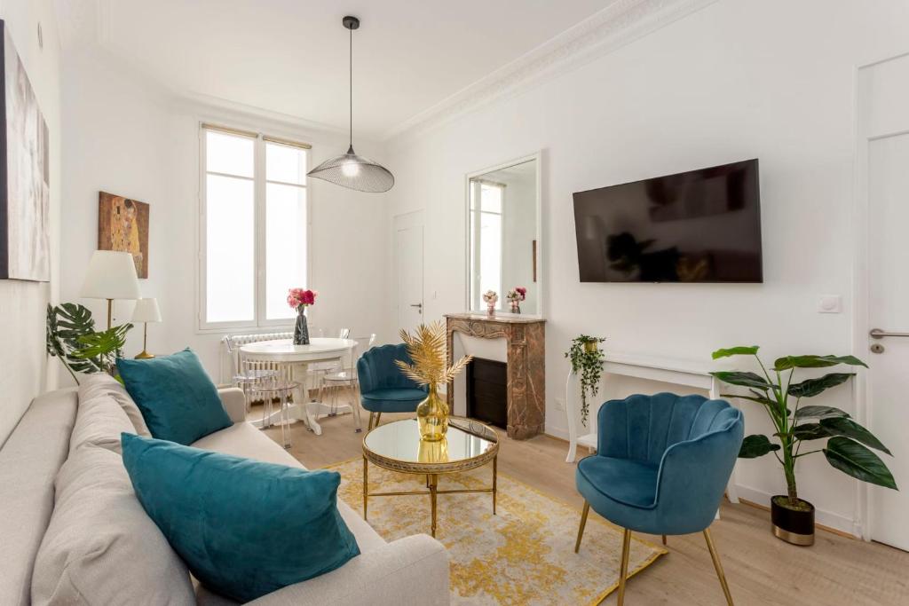 uma sala de estar com um sofá, cadeiras e uma mesa em Cosy 2 bedrooms 1 bathroom apartment - Monceau em Paris