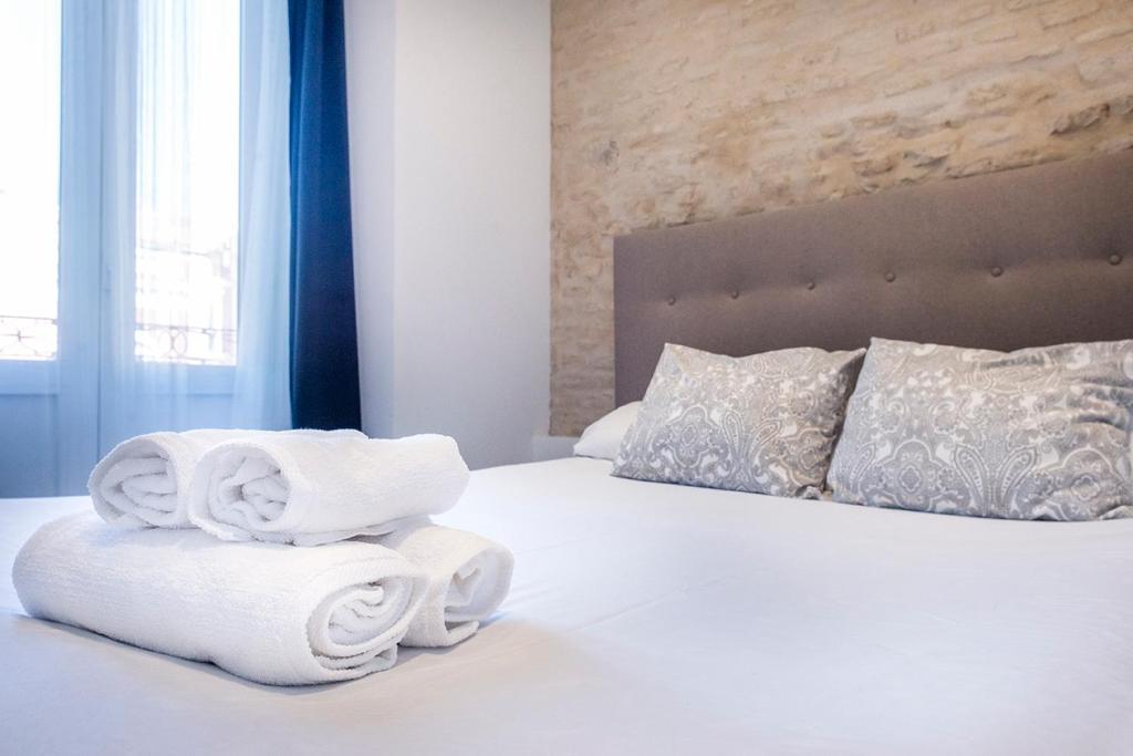 a white bed with towels on top of it at AlohaMundi Adriano in Seville