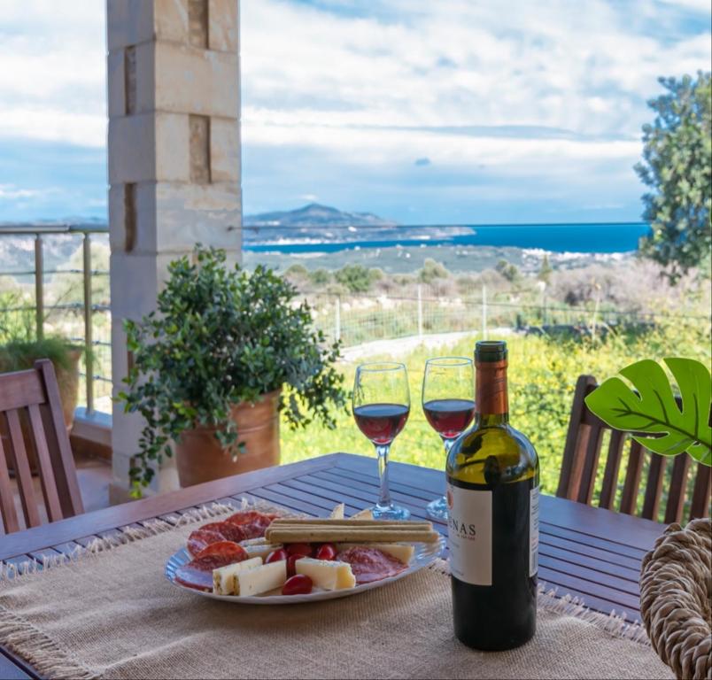 une table avec une assiette de nourriture et deux verres de vin dans l'établissement Stone villa Halepa with panoramic view., à Néon Khoríon