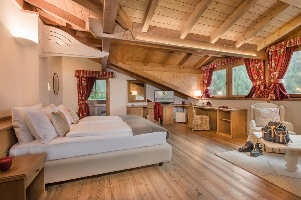 Un dormitorio con una cama grande en una habitación con techos de madera. en Bio Hotel Hermitage, en Madonna di Campiglio