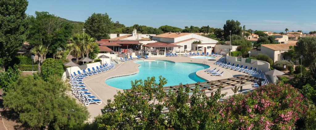 vista sulla piscina del resort con sedie a sdraio di SOWELL RESIDENCES Les Lauriers Roses a Cap d'Agde