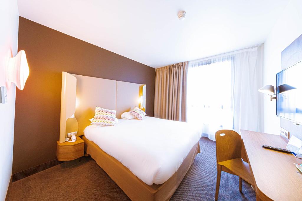 シュビイ・ラリュにあるCampanile Rungis - Orlyの大きなベッドとデスクが備わるホテルルームです。