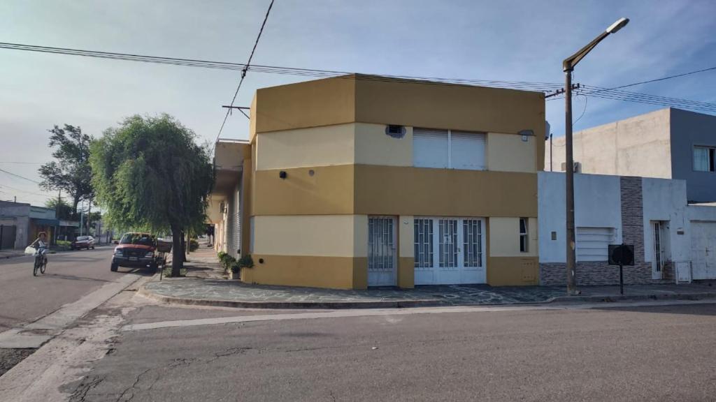 un edificio amarillo y blanco al lado de una calle en Depto. El duende en Olavarría