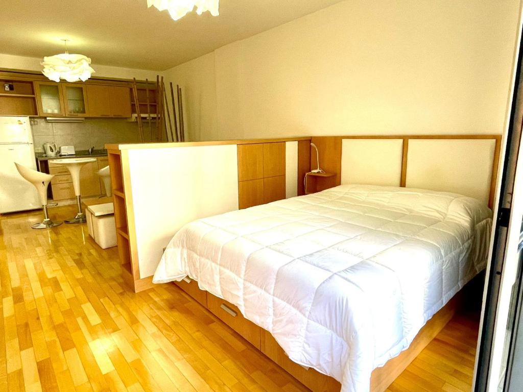 1 dormitorio con 1 cama blanca y cocina en Departamento (Las Cañitas - Palermo) en Buenos Aires