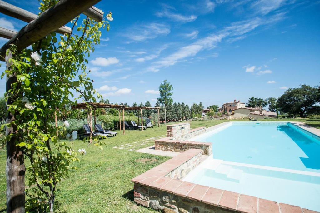an outdoor swimming pool in a yard with grass and trees at Appartamento Quercia in Trequanda