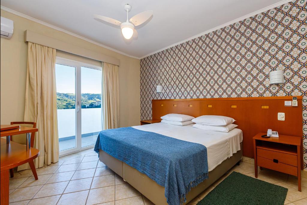 um quarto com uma cama e uma grande janela em Panorama Hotel em Águas de Lindoia