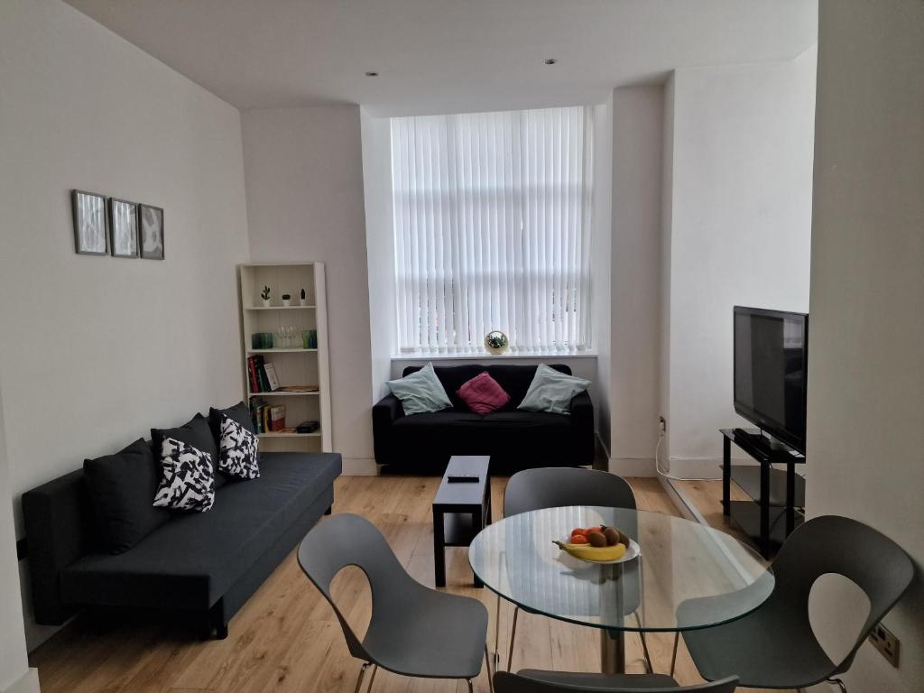 Una sala de estar con un sofá negro y una mesa. en Converted Mill Apartment, en Mánchester