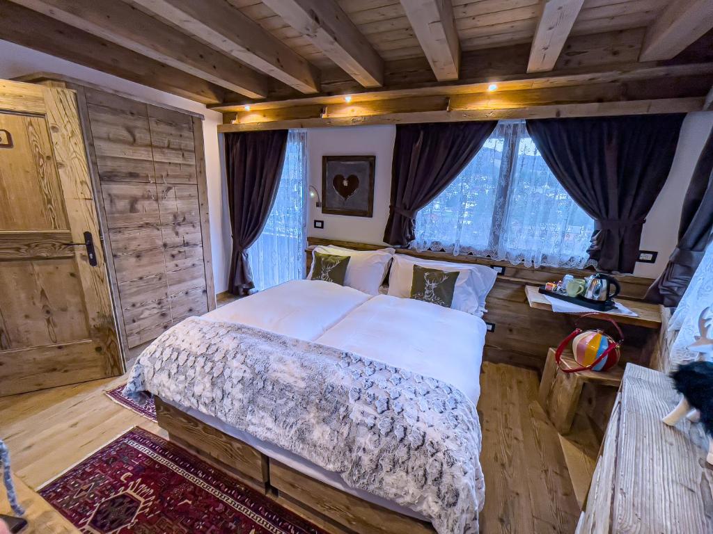 a bedroom with a large bed and some windows at Hotel da Beppe Sello in Cortina dʼAmpezzo