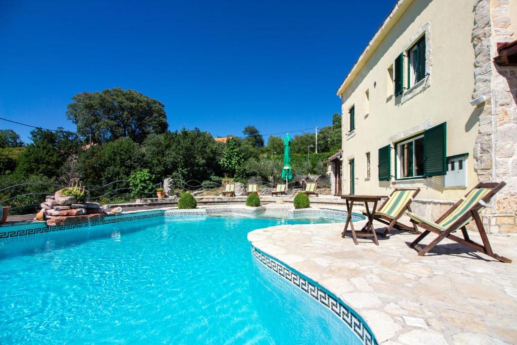uma piscina com duas cadeiras e um edifício em Magnificent Villa Olka With Private Pool and Sauna em Žeževica