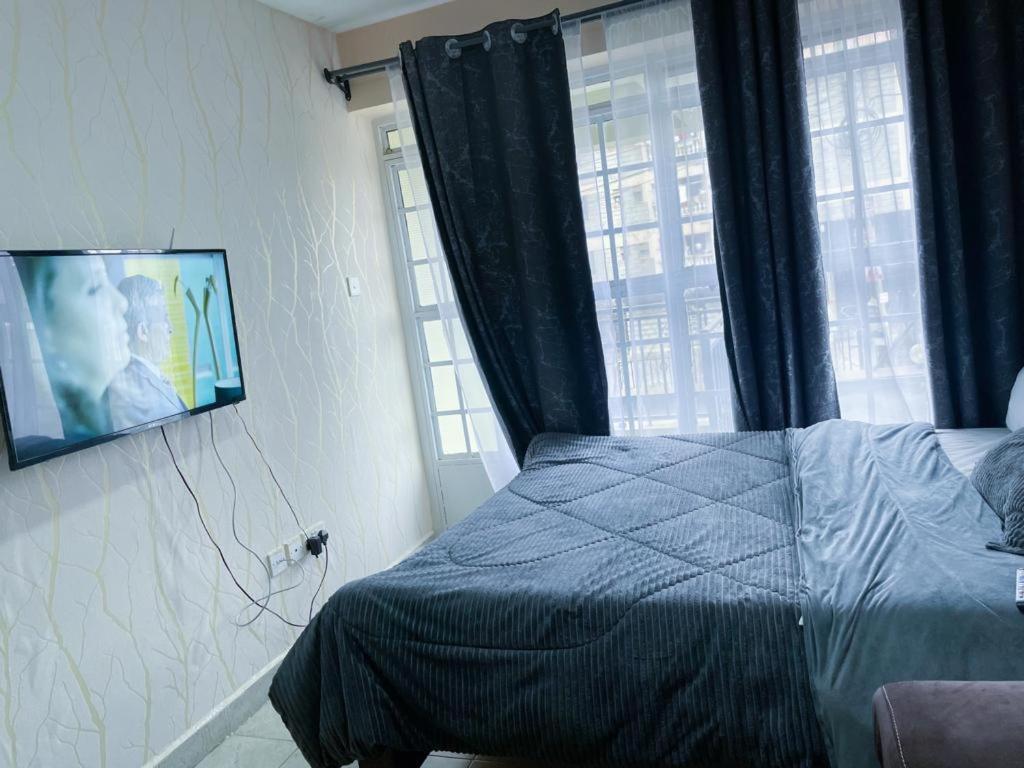 a bedroom with a bed and a tv on the wall at Ruaka studio Airbnb in Ruaka