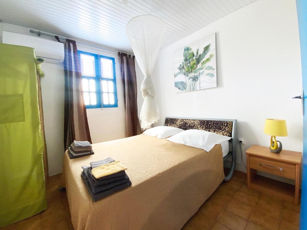 um quarto com uma cama com toalhas em Grande villa climatisée,jardin, ideale famille, groupe amis, proche port de peche,littoral em Le Diamant