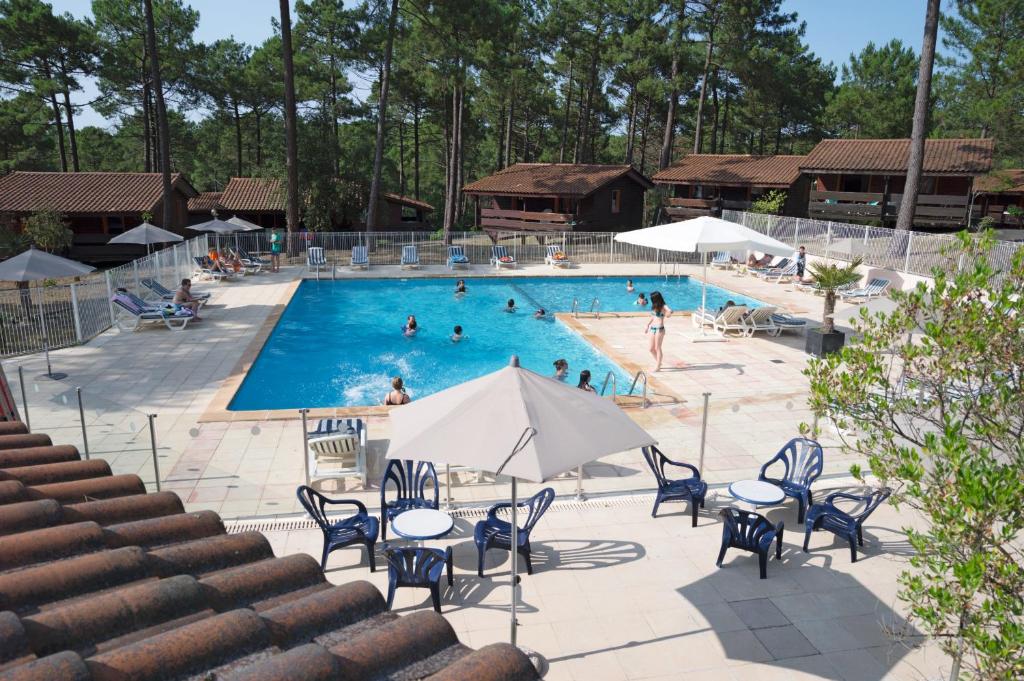 a swimming pool with blue chairs and people in it at Résidence les Sentes in Carcans