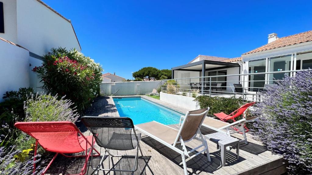 un patio con sillas y una piscina en Superbe villa avec piscine chauffée, proche mer, en Ars-en-Ré