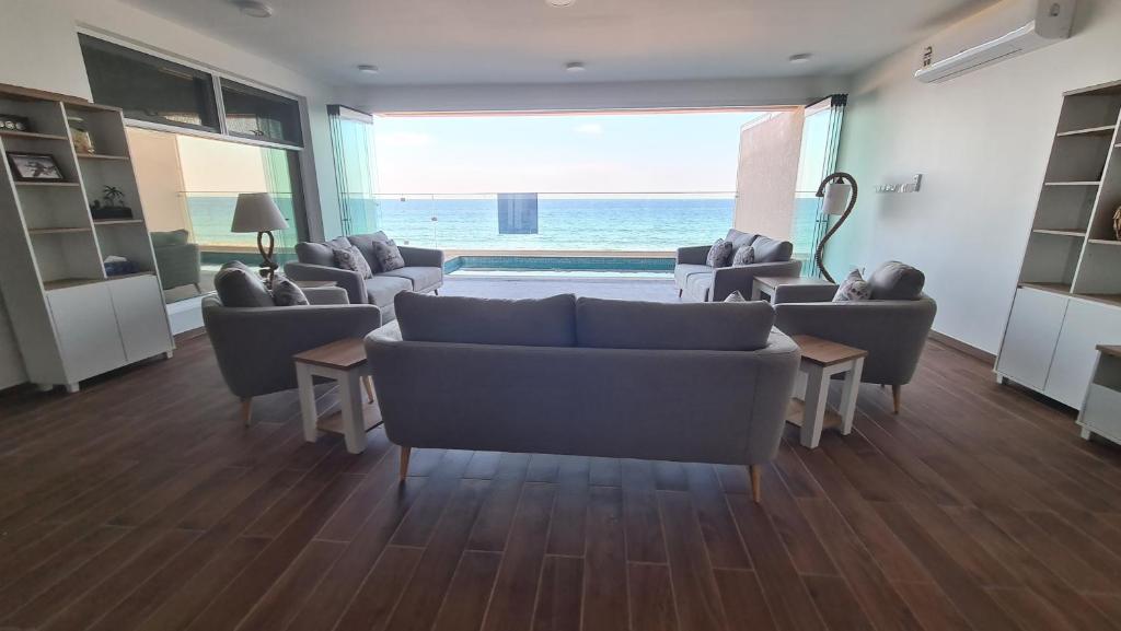 a living room with couches and a view of the ocean at Casa Del Mar Villa in As Sīfah