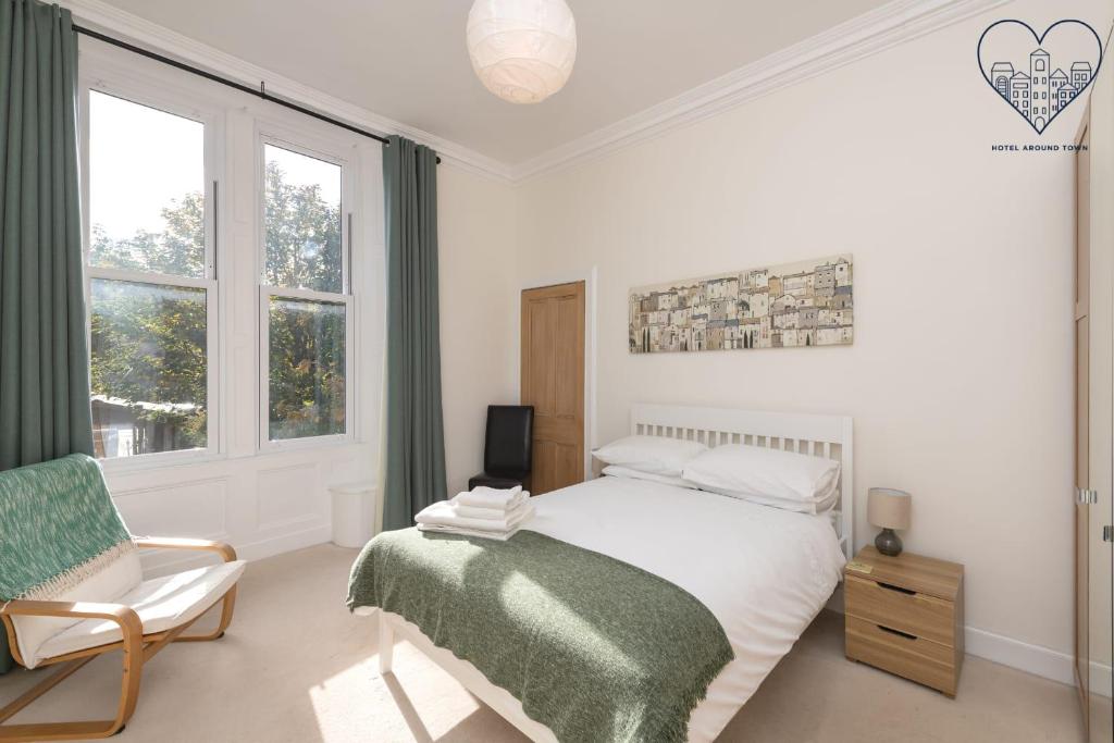 Schlafzimmer mit einem Bett, einem Stuhl und Fenstern in der Unterkunft Spacious 2 bedroom High Street apartment in North Berwick