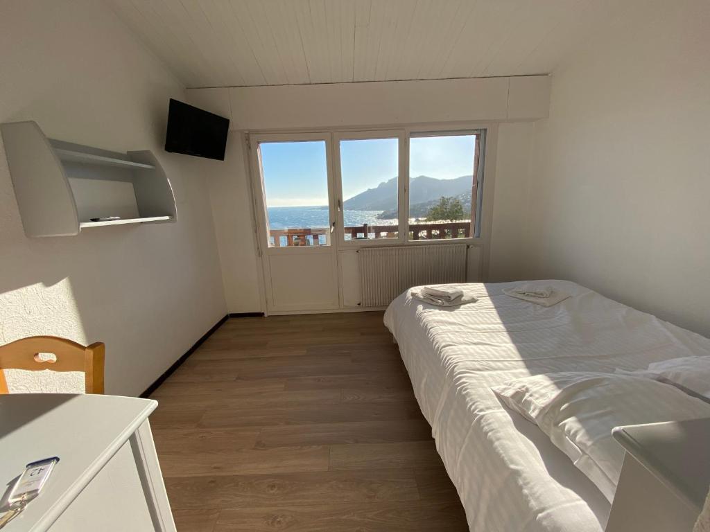 ein Schlafzimmer mit einem Bett und einem großen Fenster in der Unterkunft Village Vacances Lou Castelet in Théoule-sur-Mer