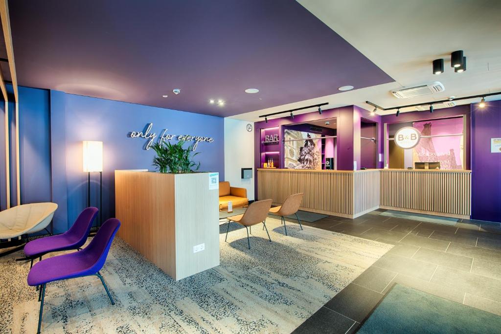 a lobby with purple walls and purple chairs at B&B Hotel Augsburg-West in Augsburg