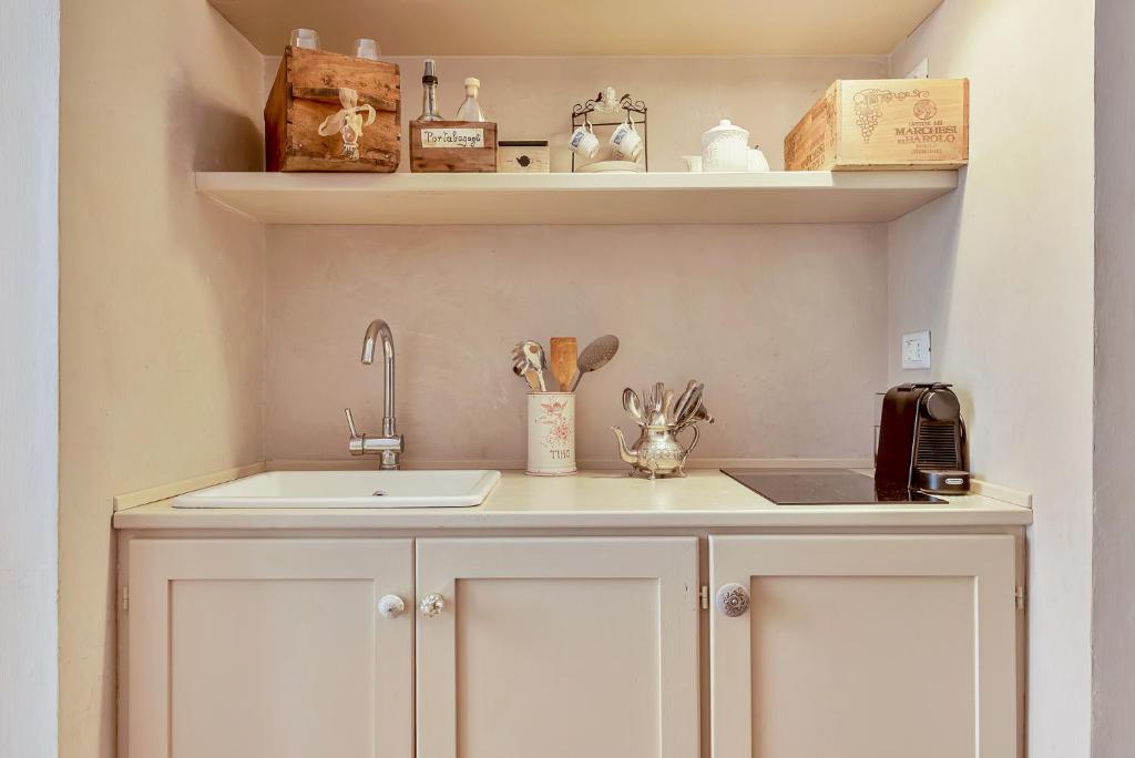 a kitchen with white cabinets and a sink and shelves at Suite Royal in La Spezia