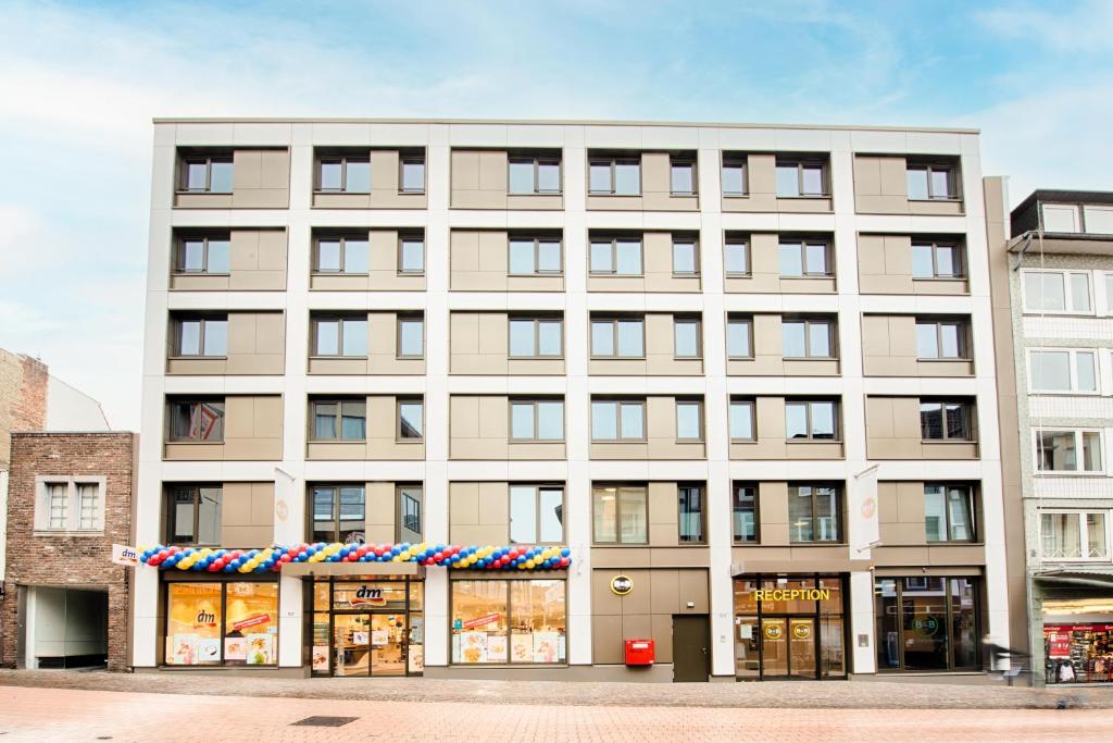 a large white building with a store front at B&B Hotel Aachen-City in Aachen