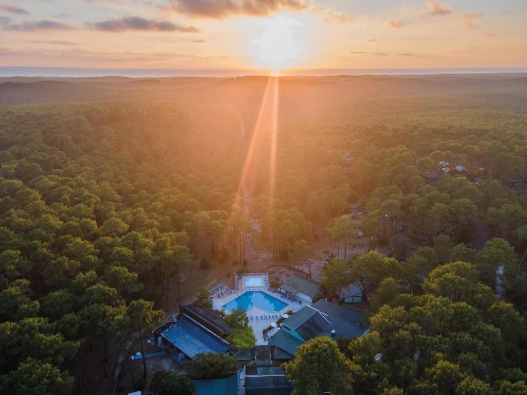 - une vue aérienne sur une maison dans les bois avec le coucher du soleil dans l'établissement Résidence les Cavales, à Carcans