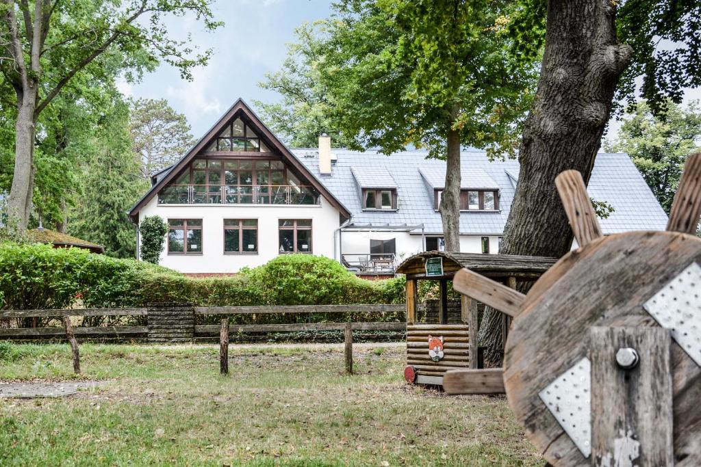 ein Haus mit einem Baum und Stühlen davor in der Unterkunft 1 Zimmer Appartement direkt am Schwielowsee in Neue Scheune