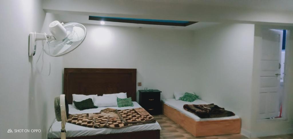 een slaapkamer met 2 bedden en een ventilator bij Hotel saspolo skardu in Skardu