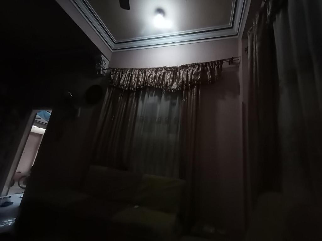 a dark room with a window with a curtain at Hossam hotil in Jazīrat al ‘Awwāmīyah