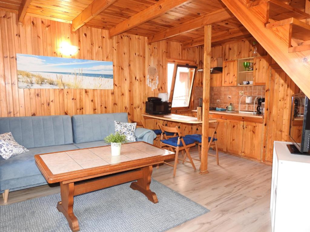 uma sala de estar com um sofá azul e uma mesa em Domki u Skrzata Drewniane em Leba