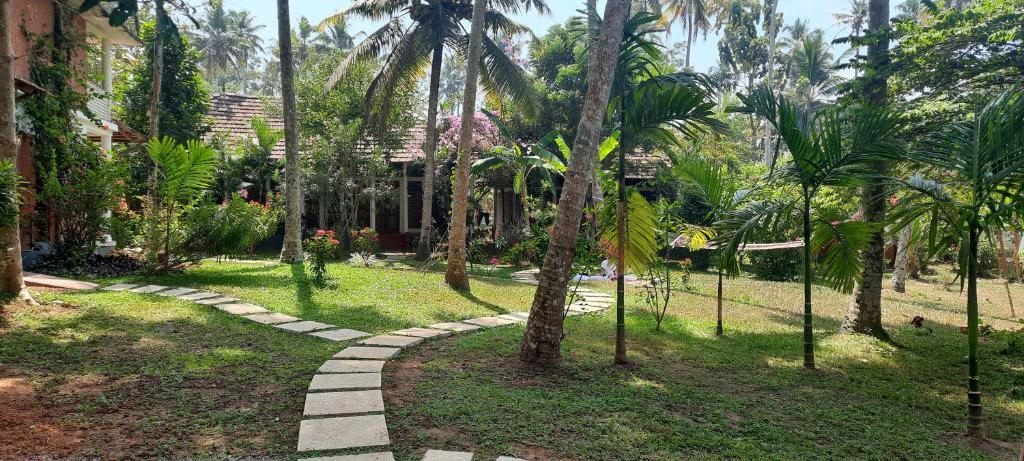 un chemin à travers un jardin planté de palmiers dans l'établissement Doctors Ayurveda Heritage, à Varkala