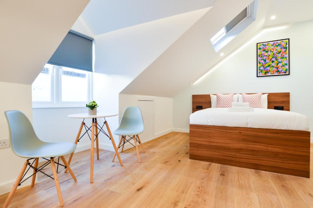 een slaapkamer met een bed en 2 stoelen en een tafel bij West Hampstead Serviced Apartments by Concept Apartments in Londen