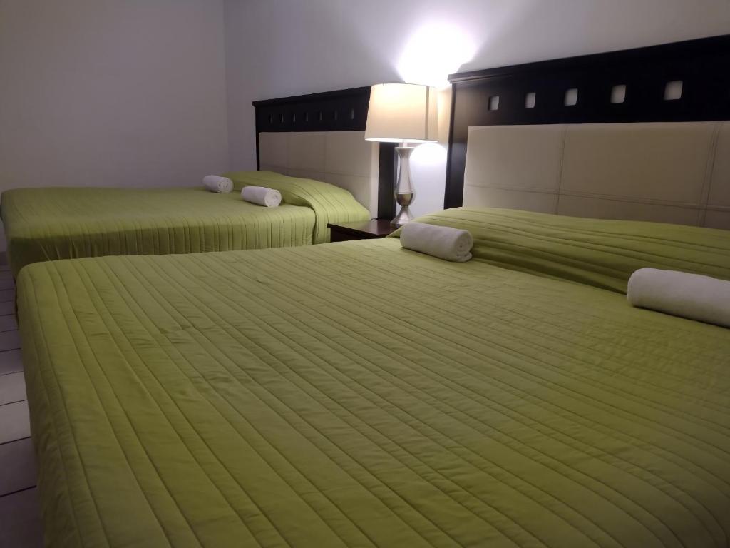 two beds in a hotel room with green sheets at Mi Depa Cascada in Ciudad Valles