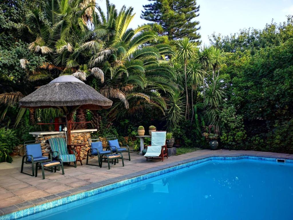 a swimming pool with chairs and a gazebo next to a swimming pool at Santika Getaway Cottage Stellenbosch in Stellenbosch