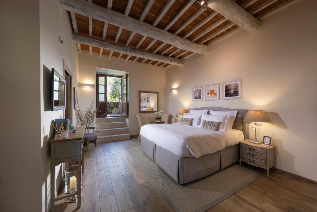 a bedroom with a bed and a desk and a window at Borgo Argiano in Castelnuovo Berardenga