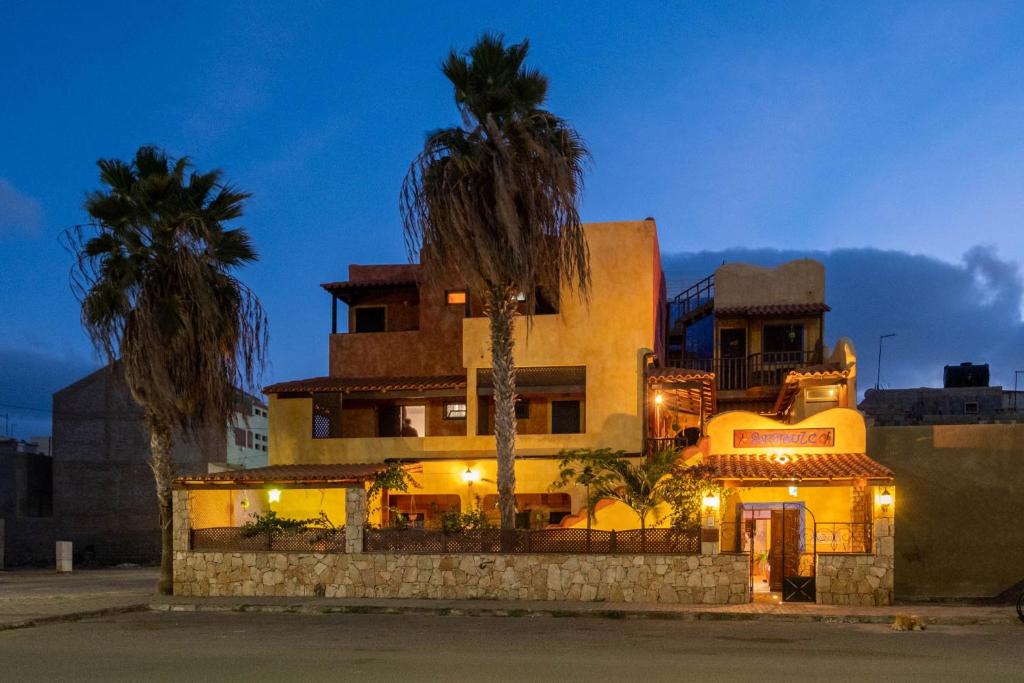 a building with two palm trees in front of it at Sakaroule B&B in Santa Maria