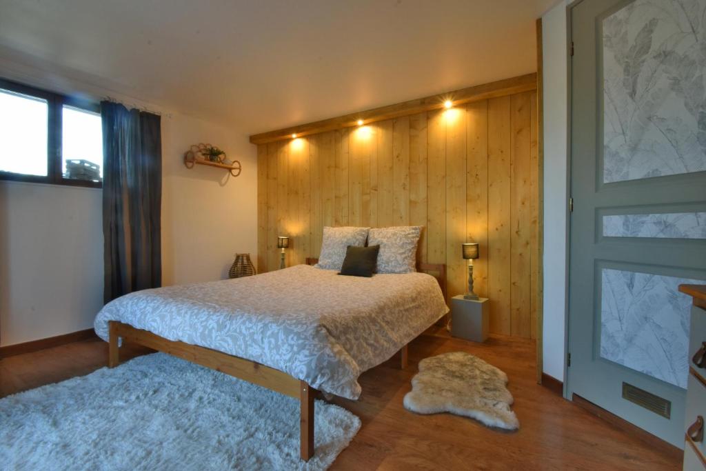 een slaapkamer met een bed met een houten muur bij Chambre d'hôtes La Détente - Domaine la Rose des vents in Castelnau-sur-lʼAuvignon