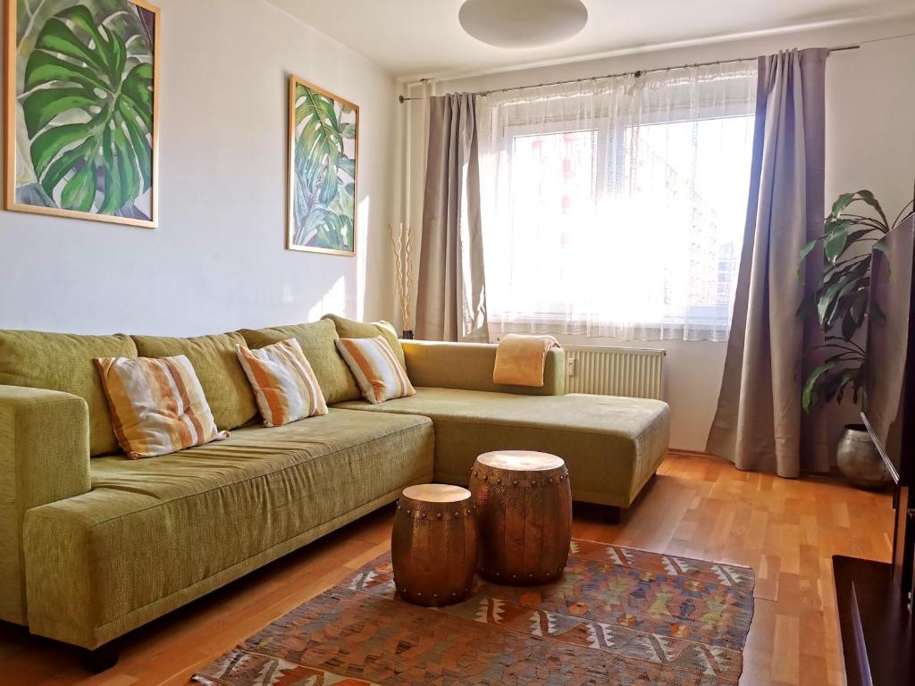 a living room with a green couch and two logs at CozyHome Retro Apartment in Bratislava