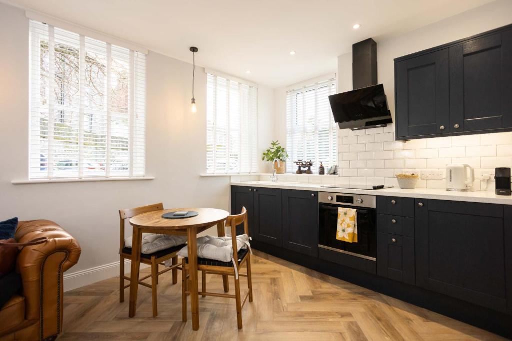 a kitchen with black cabinets and a table with chairs at The Weights and Measures Office in Berwick-Upon-Tweed