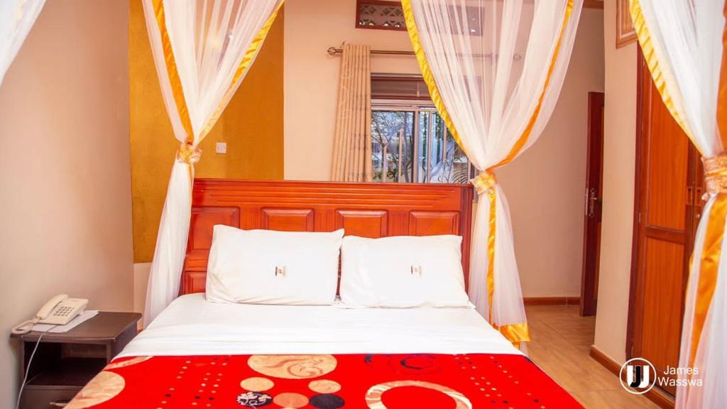 - une chambre avec un lit et une couverture rouge dans l'établissement Model Gardens Sonde, à Kampala