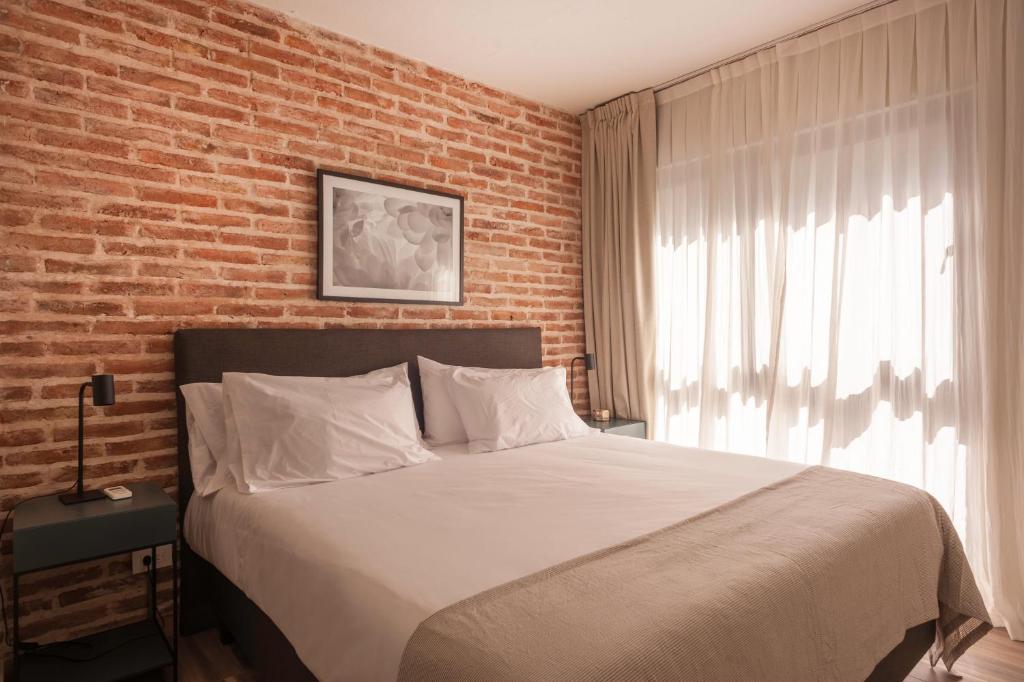 1 dormitorio con 1 cama grande y pared de ladrillo en Cozy & Modern Luxe Apartment -La Galerie San Telmo- 228 en Buenos Aires