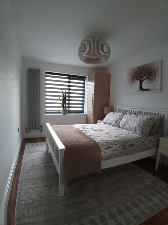 a white bedroom with a large bed and a window at The Annexe Cheadle Hulme in Cheadle Hulme