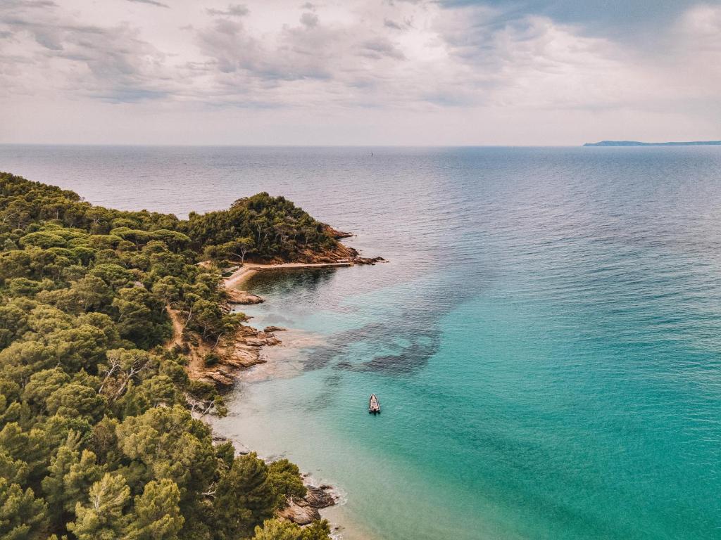 an island in the ocean with a boat in the water at La Résidence du Bailli in Rayol-Canadel-sur-Mer