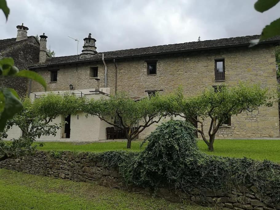 un antiguo edificio de piedra con árboles delante de él en Casa Rural Barangua en el Pirineo Aragonés en Santa Cruz de la Serós