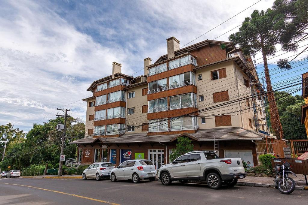 un grande edificio con macchine parcheggiate di fronte di Rosa Edifício Parque da Vinícola a Gramado