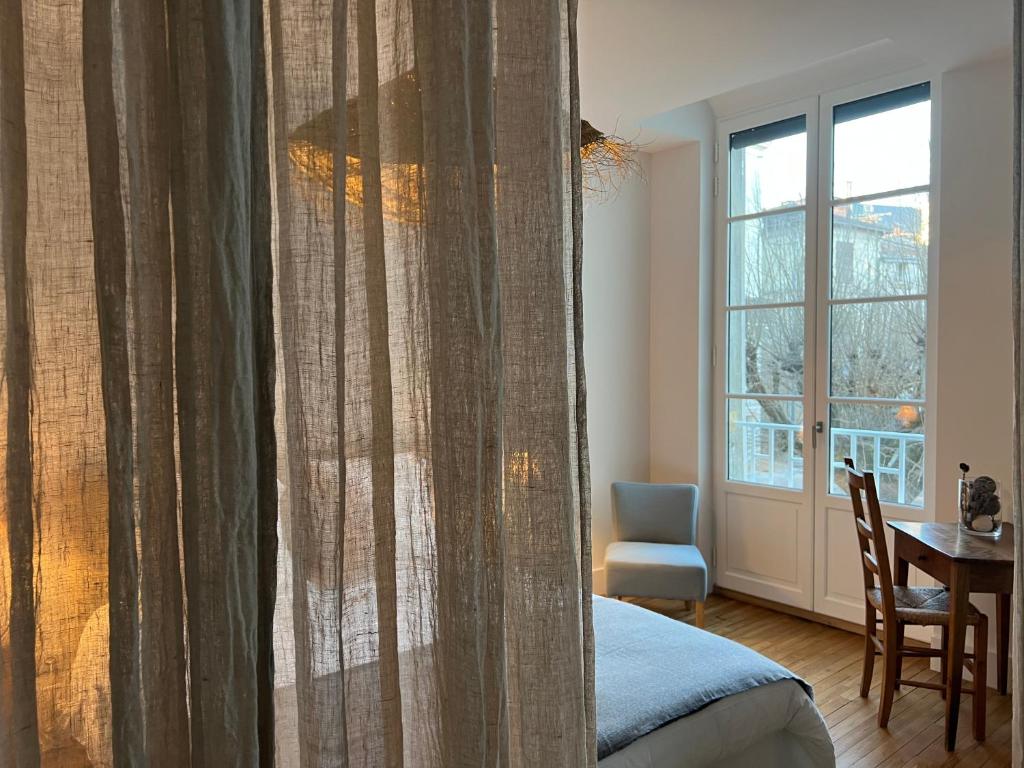 sypialnia z łóżkiem, stołem i oknem w obiekcie Luxe et Charme - Le Carré Saint-Silain - Meublé de tourisme 3 étoiles w mieście Périgueux